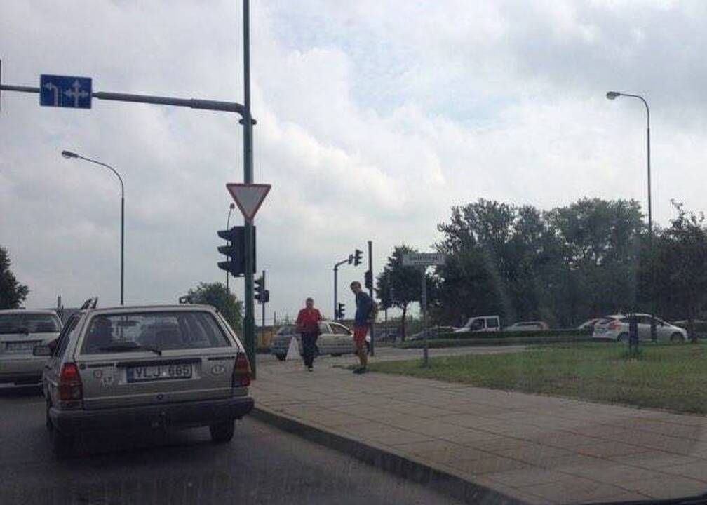 Netikėtumas: vairuotojai sutrinka, kai sankryžoje prie jų prieina nepažįstamasis ir įbruka į rankas vėliavėlę.