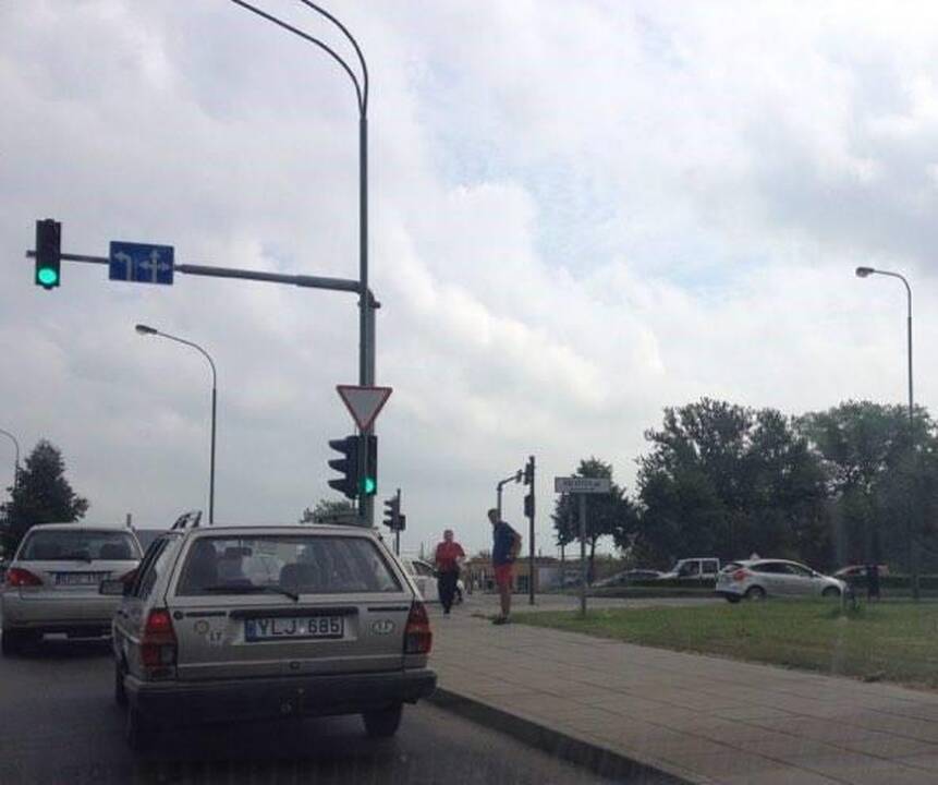Netikėtumas: vairuotojai sutrinka, kai sankryžoje prie jų prieina nepažįstamasis ir įbruka į rankas vėliavėlę.
